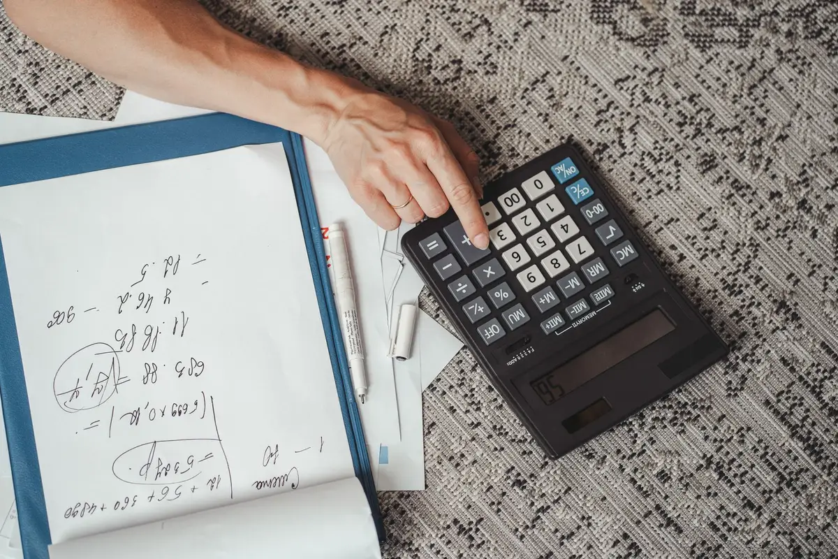 Personne calculant un budget avec papiers et calculatrice