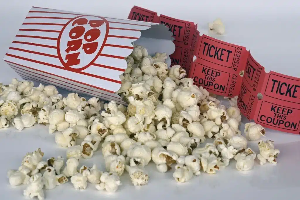 Salle de cinéma anonyme avec public, pop-corn et billets, écran lumineux en arrière-plan